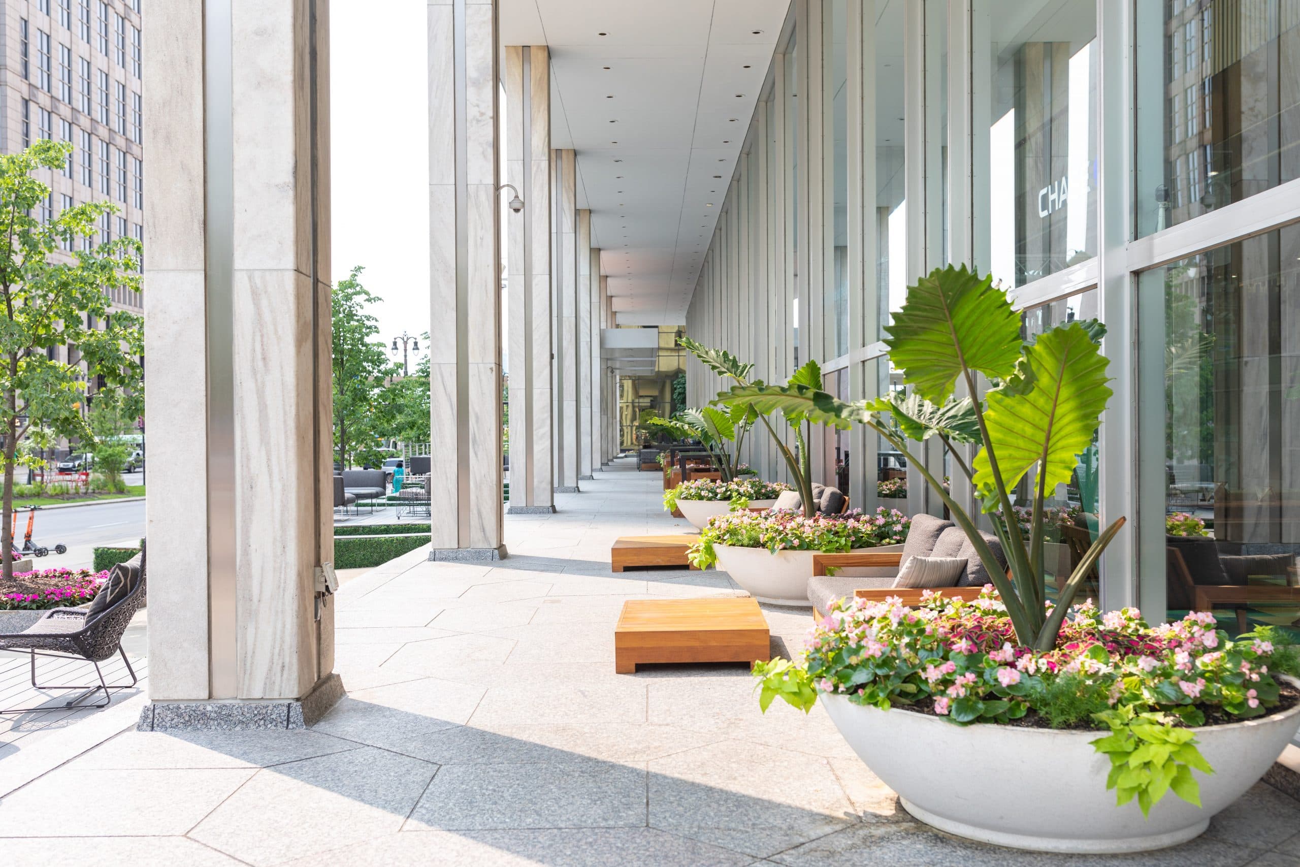 Chase Tower Lobby + Patio featuring a large live planter, and outdoor patio furniture in front of floor to ceiling windows, facing Woodward Ave.